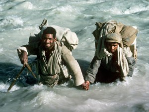 Balti porters crossing a river during the difficult trek in to the base of The Ogre (Photo: Doug Scott)