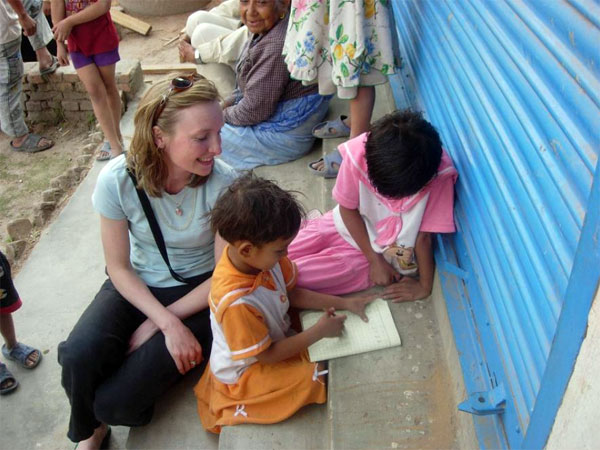 CHANCE founder Tina Stacey helps kids do homework at a village in the Kathmandu Valley (Photo: CHANCE)