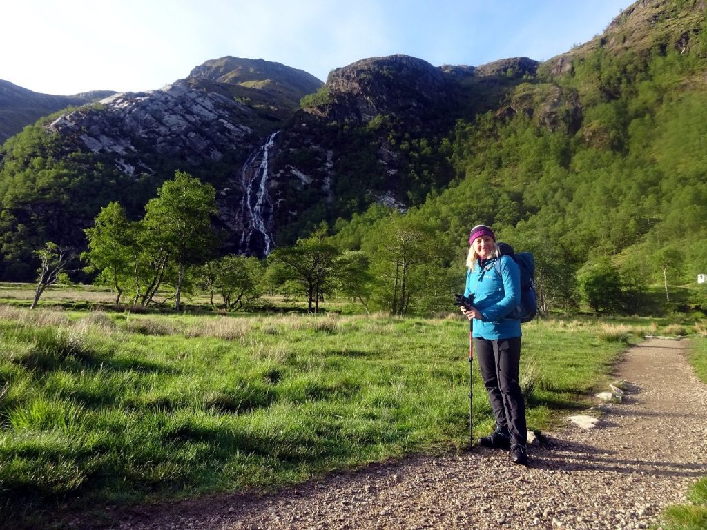 Edita in the wild camping meadow in Glen Nevis, with the waterfall of An Steall behind